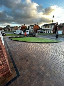 GB Surfacing crew laying block paving and artificial turf driveway island on residential estate